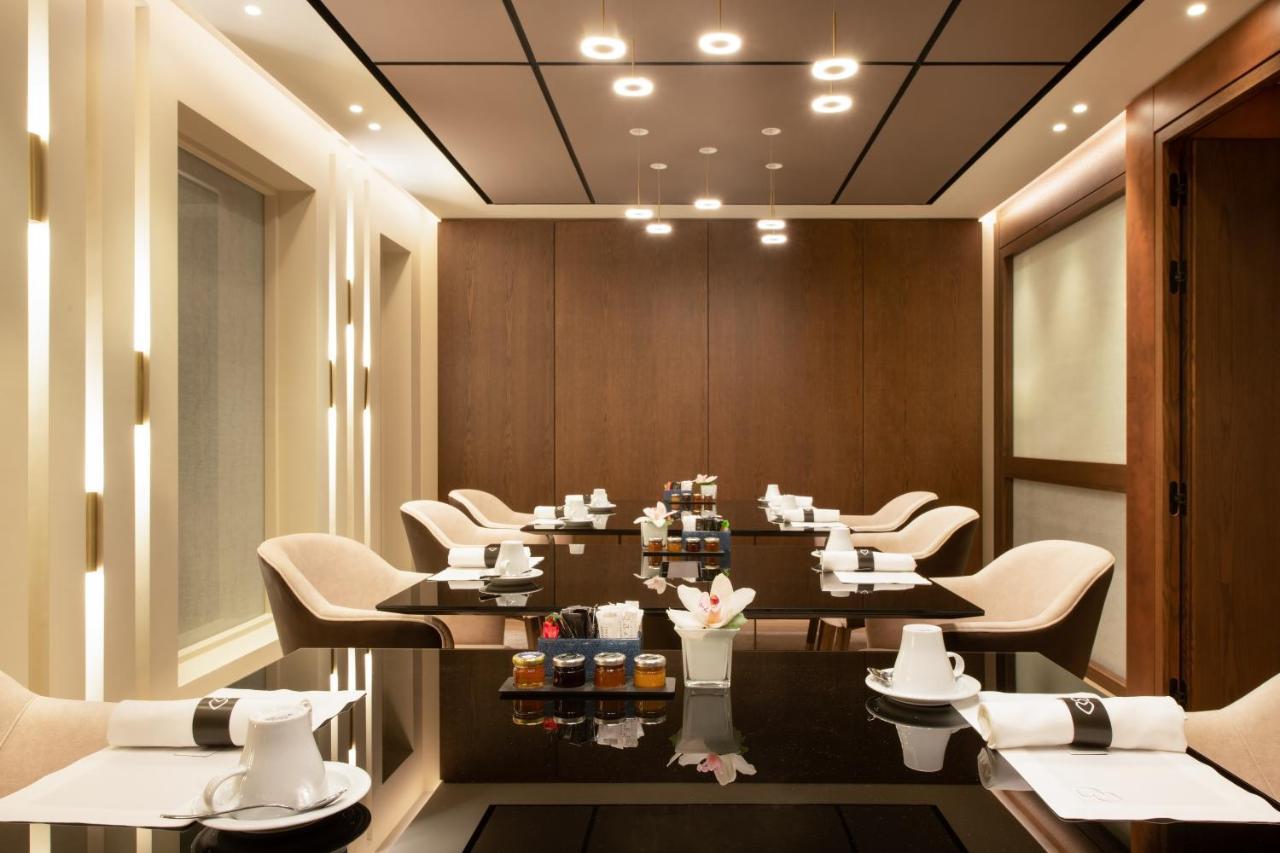 Sofitel Athens Airport Hotel Spata  Luaran gambar The photo shows a modern and elegantly designed dining or meeting room. It features a sleek, dark table surrounded by several light-colored chairs. The walls are adorned with warm wood paneling, and the ceiling has recessed lighting that adds a soft 