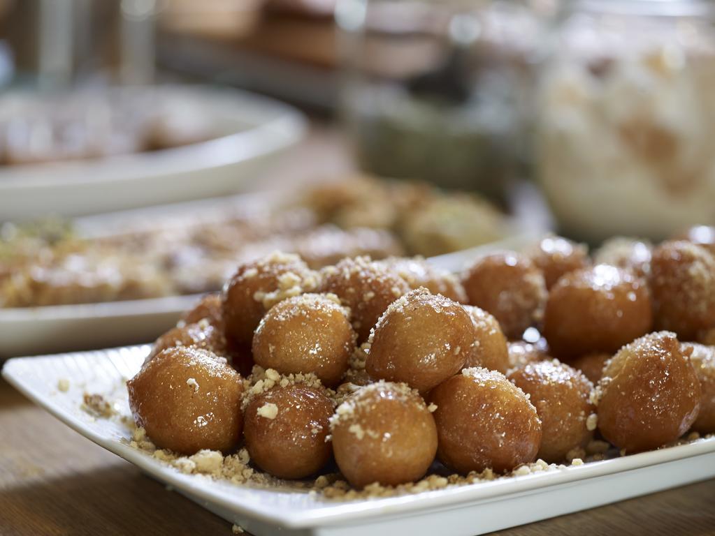 Sofitel Athens Airport Hotel Spata  Luaran gambar The photo shows a plate of small, round, golden-brown sweets, which appear to be deep-fried dough balls. They are coated in a layer of granulated sugar or crushed nuts, giving them a sweet and crunchy appearance. In the background, there are other di