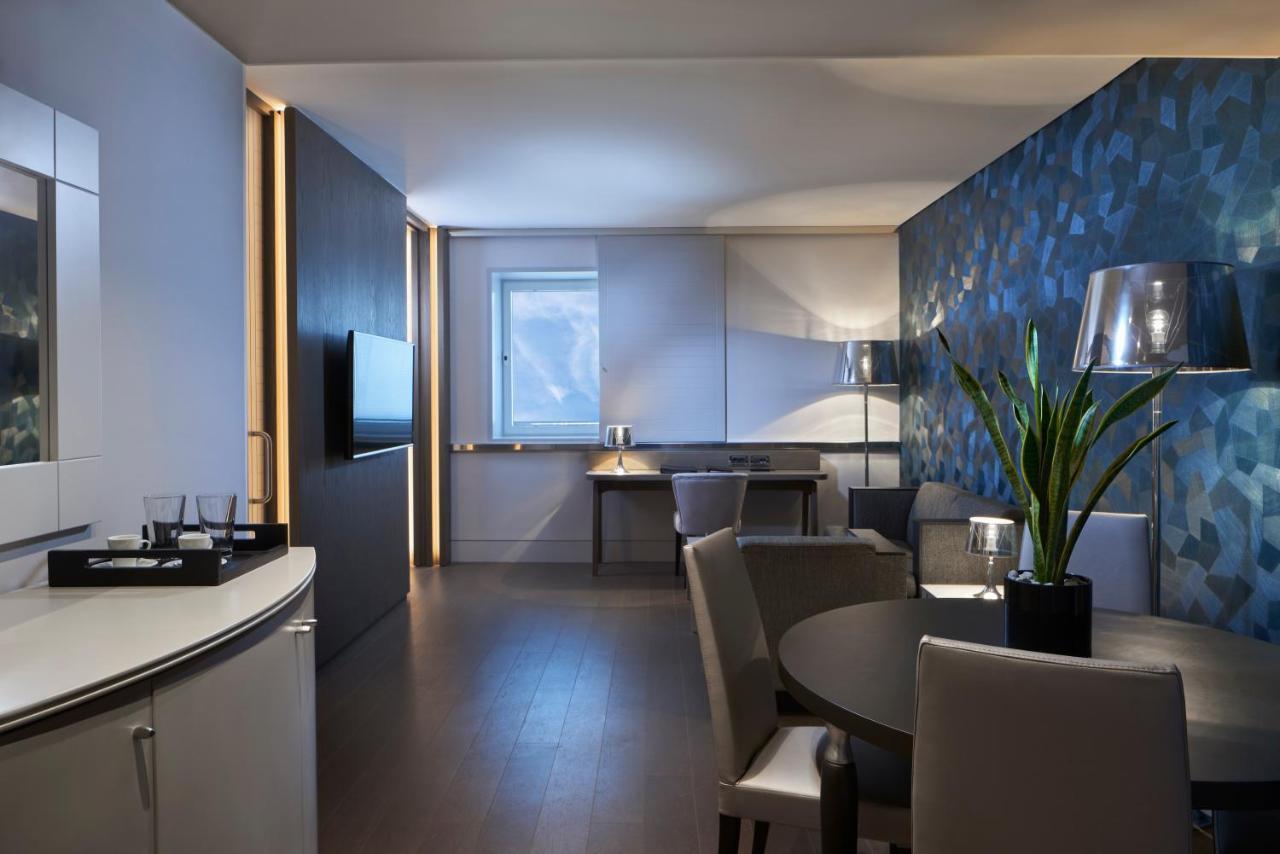 Sofitel Athens Airport Hotel Spata  Luaran gambar The photo shows a modern living space, likely a hotel suite or an upscale apartment. The room features a stylish and minimalist design with a combination of light and dark elements. 

- **Seating Area:** There are a couple of comfortable-looking chai